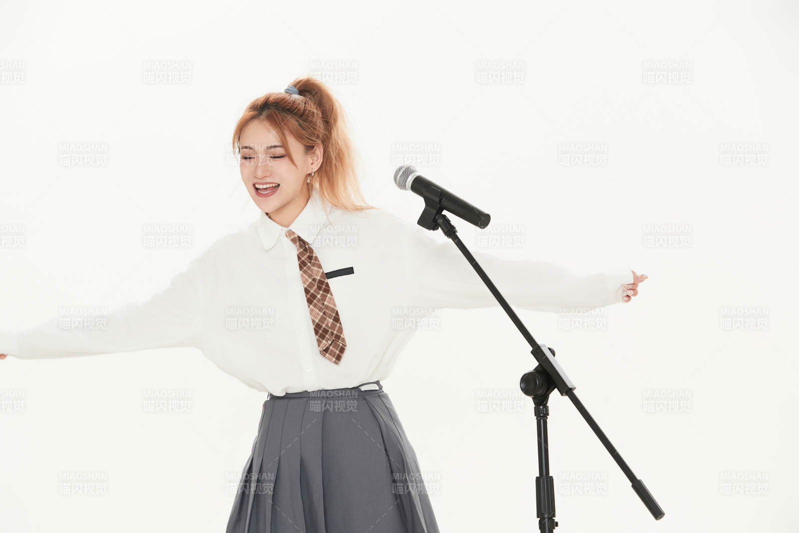 白色背景下站在麦克风前唱歌的亚洲女性图片