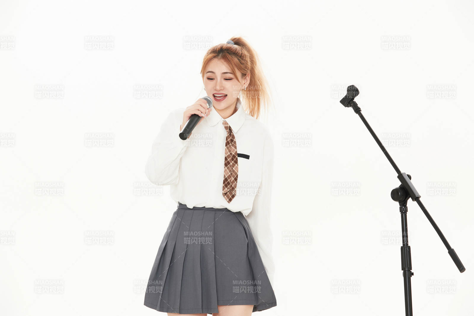 白色背景下站在麦克风前唱歌的亚洲女性图片