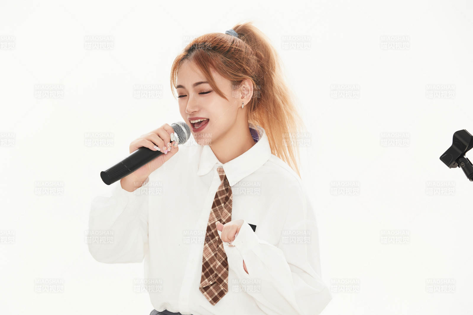白色背景下站在麦克风前唱歌的亚洲女性图片