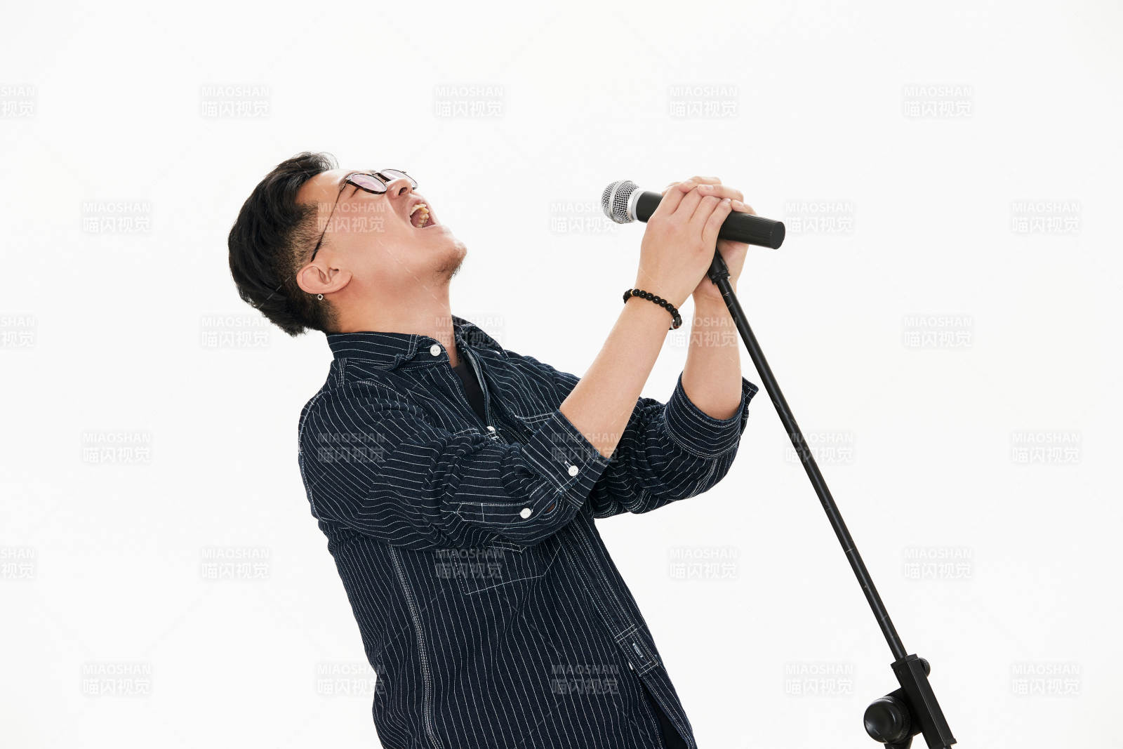 白色背景下站在麦克风前唱歌的亚洲男性图片