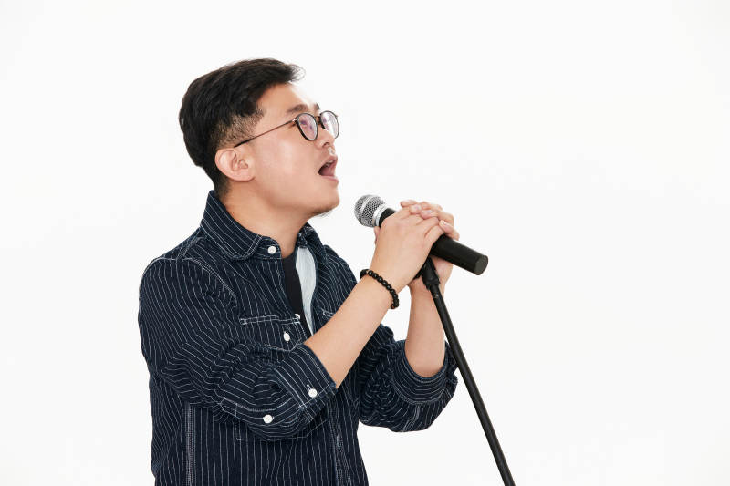 白色背景下站在麦克风前唱歌的亚洲男性图片