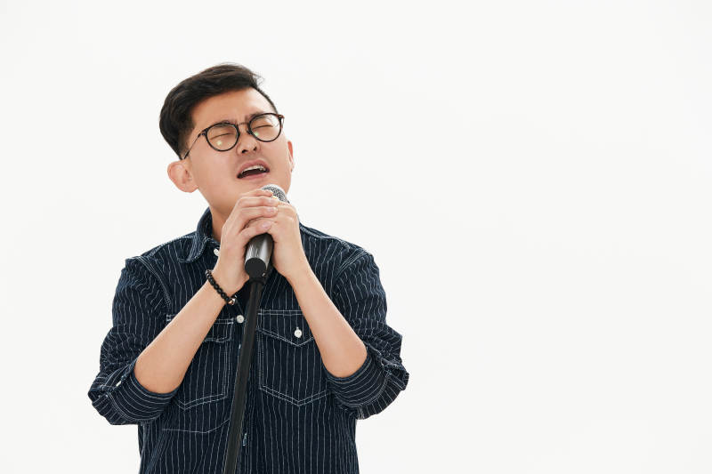 白色背景下站在麦克风前唱歌的亚洲男性图片