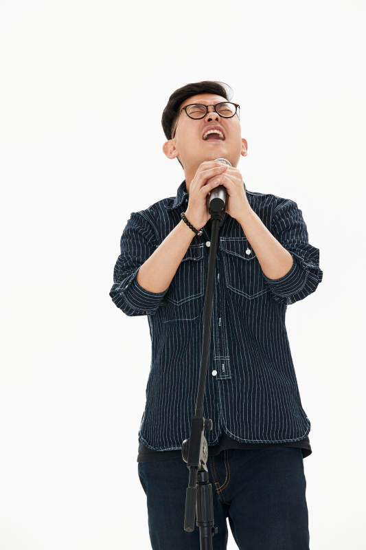 白色背景下站在麦克风前唱歌的亚洲男性图片