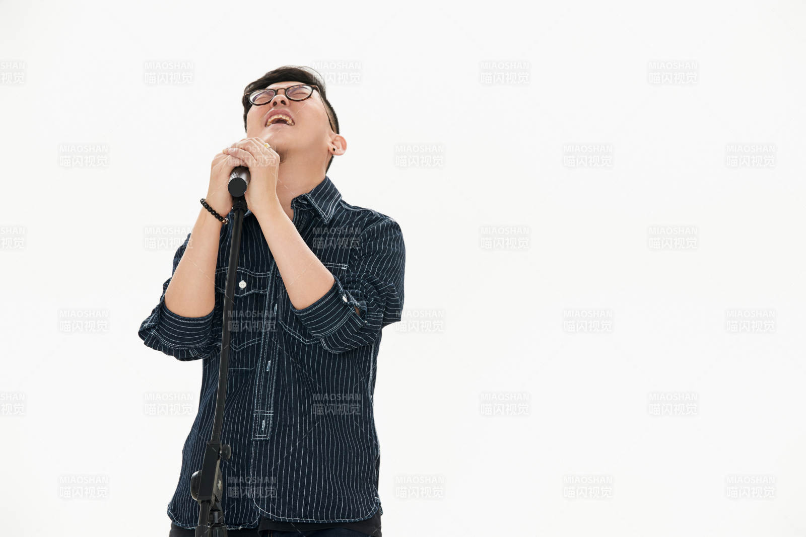 白色背景下站在麦克风前唱歌的亚洲男性图片