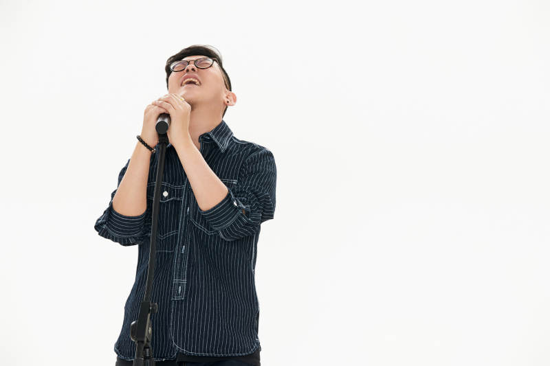 白色背景下站在麦克风前唱歌的亚洲男性图片