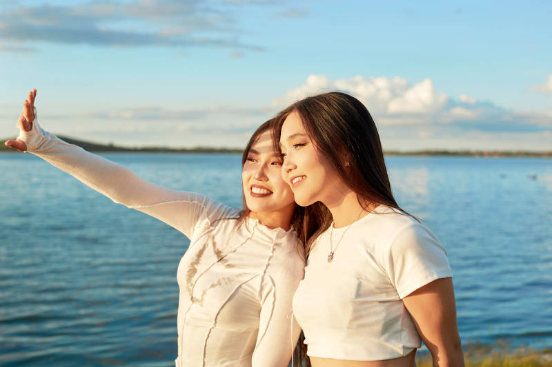 在旅游区湖边打卡点拍照的美女闺蜜图片