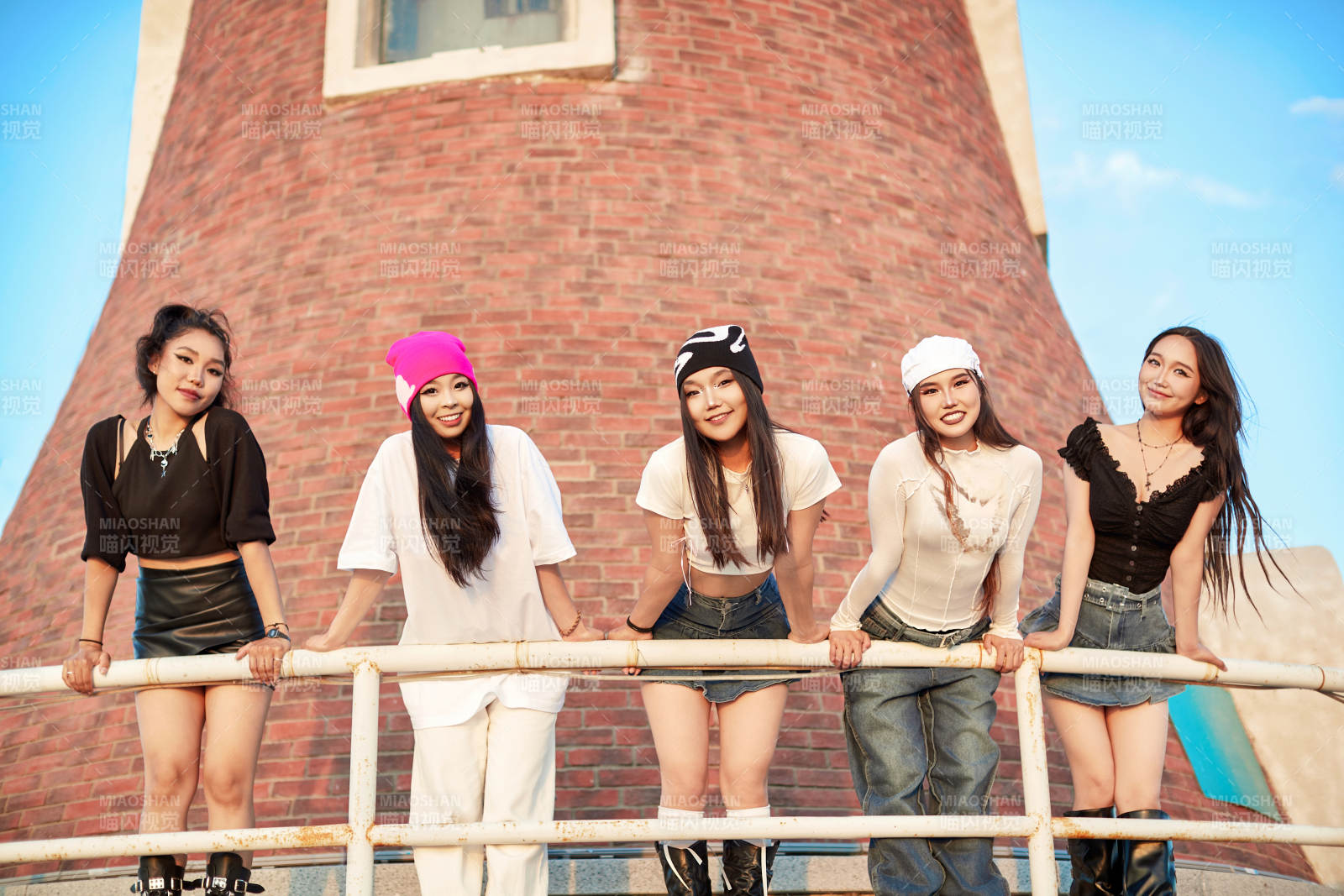 盛夏在草原湖边灯塔上拍照游玩的姑娘们图片