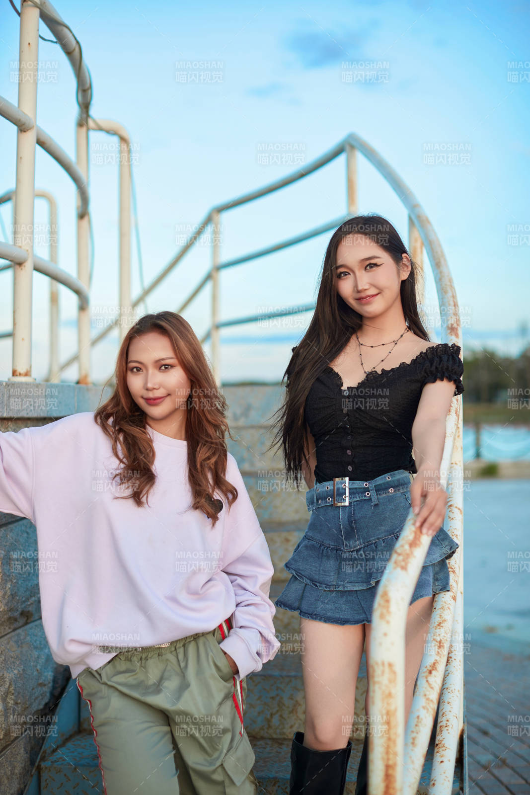 盛夏在草原湖边灯塔上拍照游玩的姑娘们图片