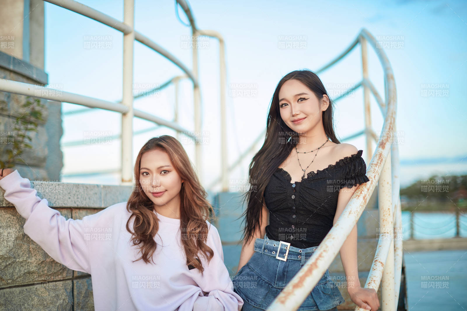 盛夏在草原湖边灯塔上拍照游玩的姑娘们图片