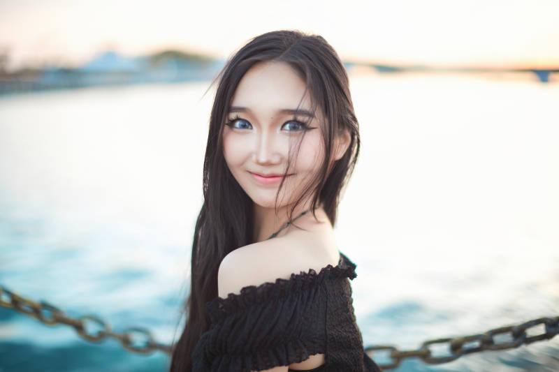 夕阳湖边打卡点拍照的美丽亚洲女性图片