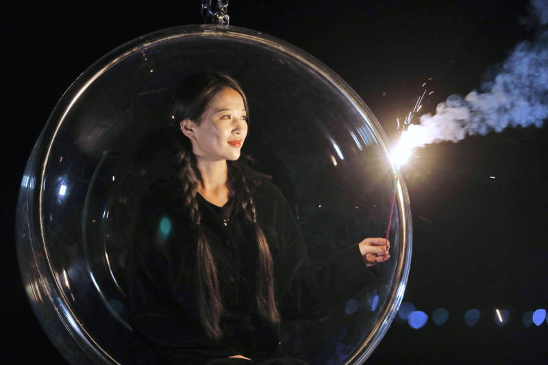 夜晚坐在透明秋千上燃放仙女棒的可爱少女图片