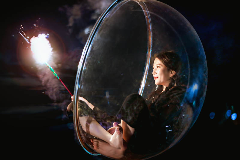 夜晚坐在透明秋千上燃放仙女棒的可爱少女图片