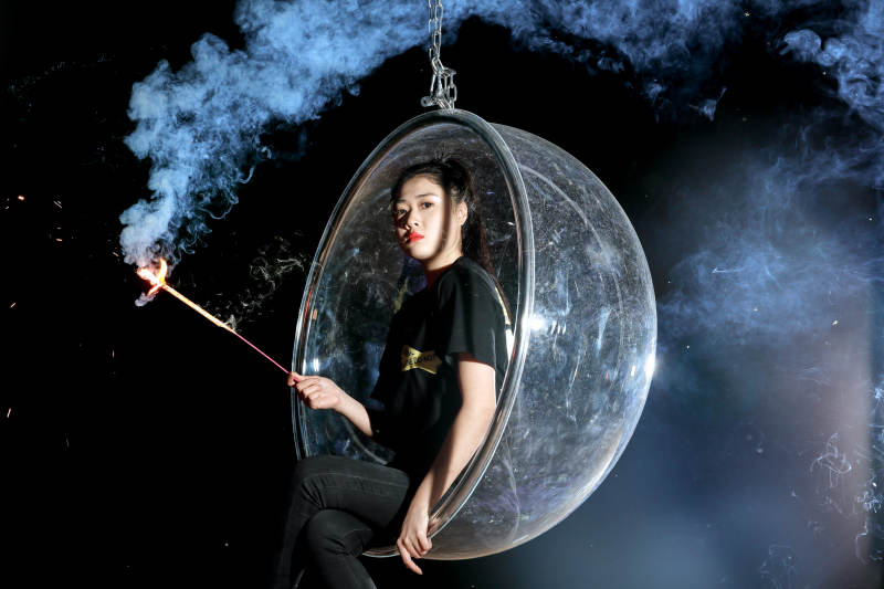 夜晚坐在透明秋千上燃放仙女棒的可爱少女图片