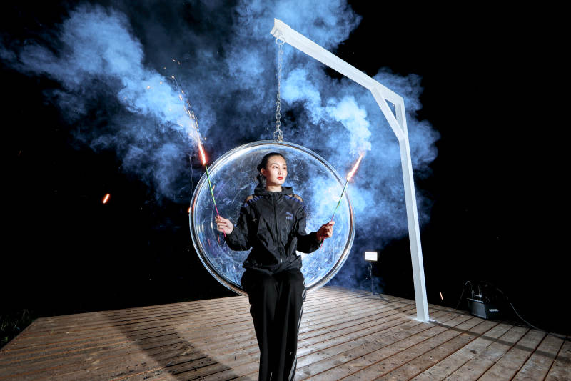 夜晚坐在透明秋千上燃放仙女棒的可爱少女图片