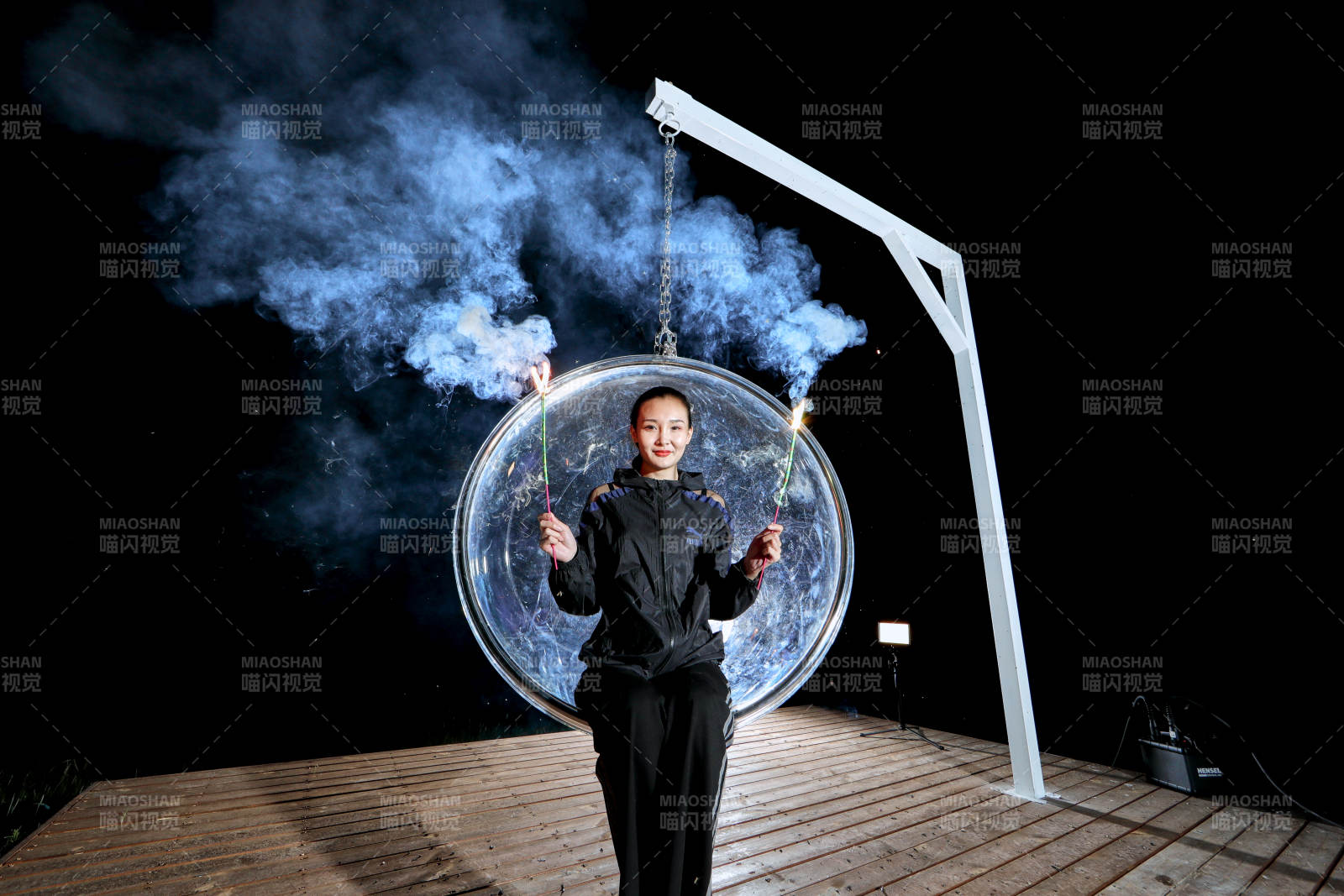 夜晚坐在透明秋千上燃放仙女棒的可爱少女图片