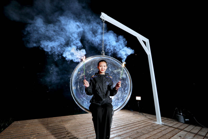 夜晚坐在透明秋千上燃放仙女棒的可爱少女图片