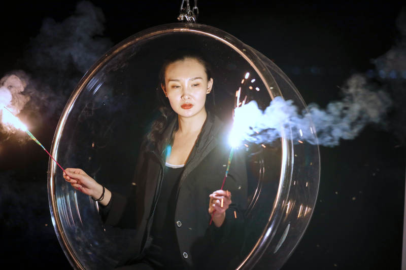 夜晚坐在透明秋千上燃放仙女棒的可爱少女图片