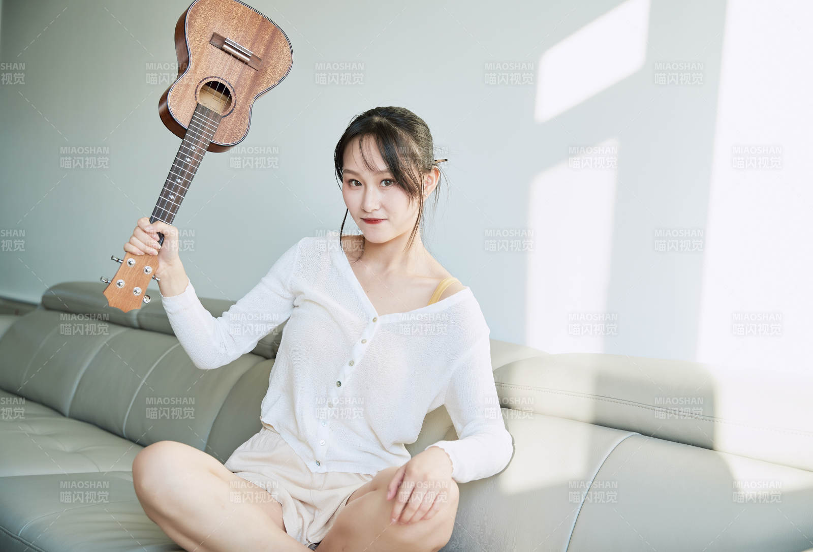 坐在沙发上弹奏尤克里里的少女图片