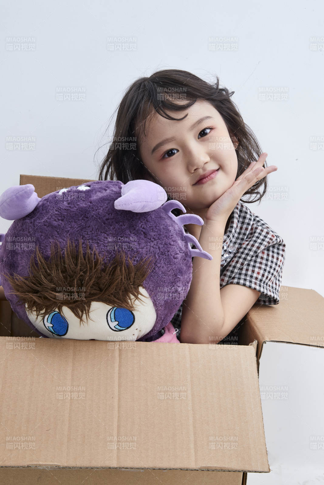 黑色背景里坐在凳子上抱着娃娃玩耍的可爱亚洲小女孩儿童图片