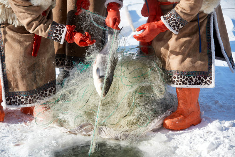 寒冷的冬季在冰冻的湖面上凿冰捕鱼图片
