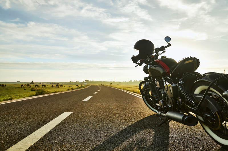 清晨朝阳下停靠在公路上的复古摩托车图片