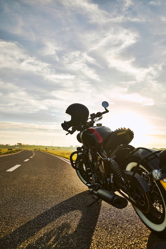 清晨朝阳下停靠在公路上的复古摩托车图片