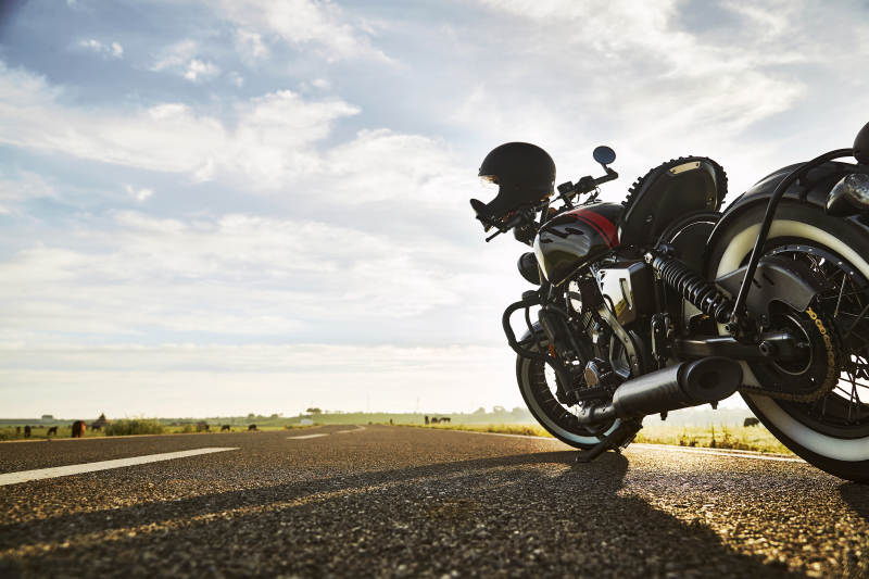 清晨朝阳下停靠在公路上的复古摩托车图片