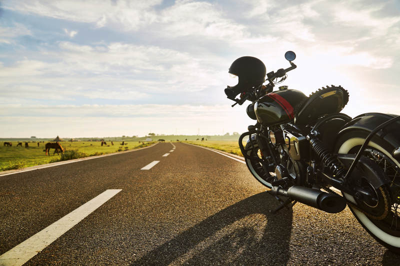 清晨朝阳下停靠在公路上的复古摩托车图片