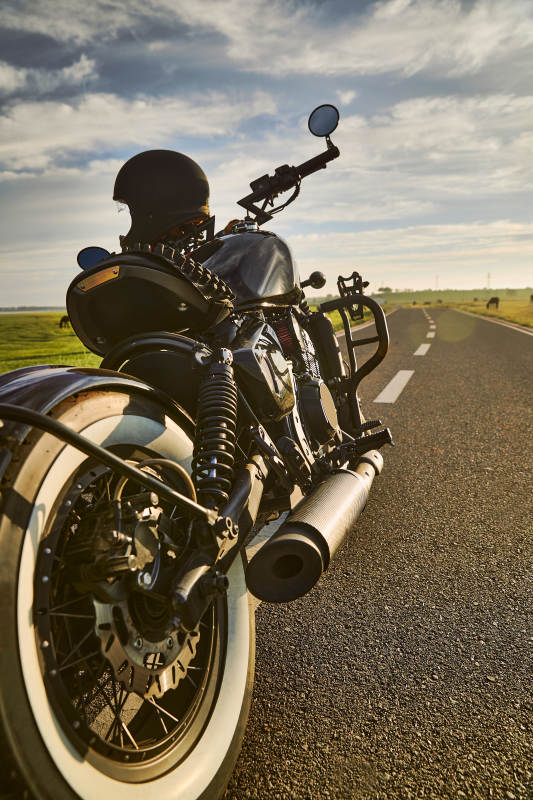 清晨朝阳下停靠在公路上的复古摩托车图片