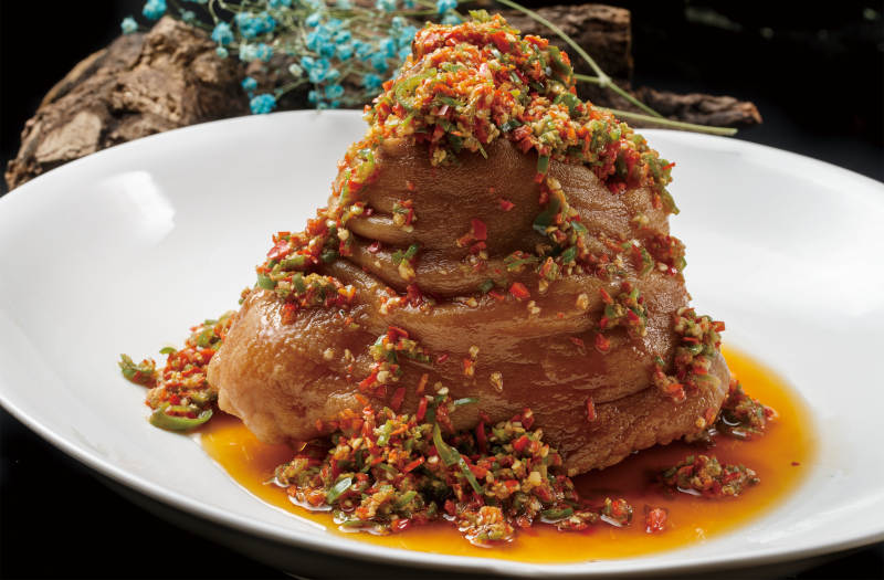 圆形白色瓷盘装的椒麻红烧猪肘图片