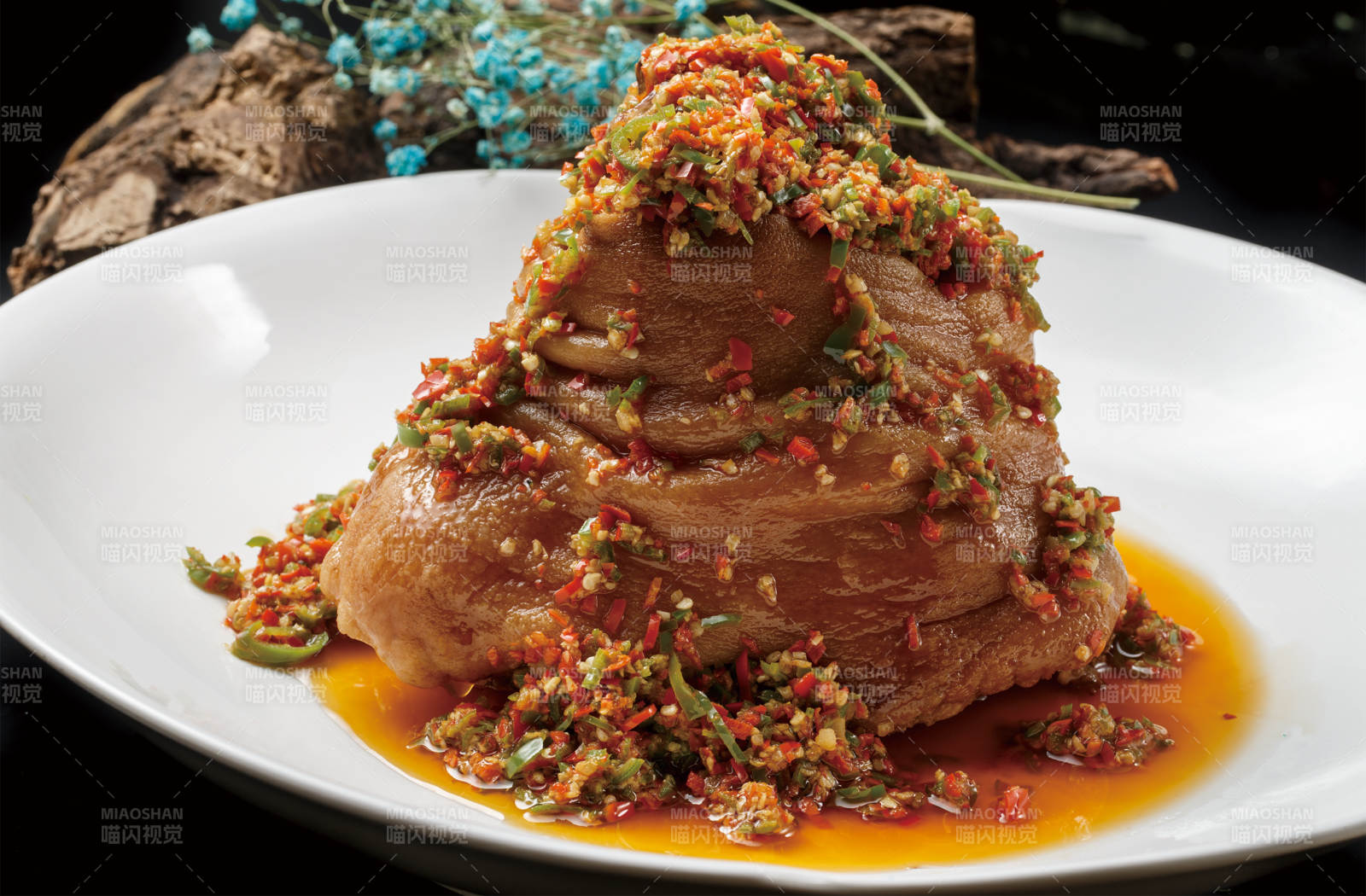 圆形白色瓷盘装的椒麻红烧猪肘图片