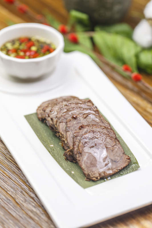 长方形白瓷盘装的蘸汁牛脊肉图片