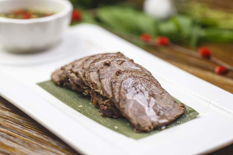 长方形白瓷盘装的蘸汁牛脊肉图片