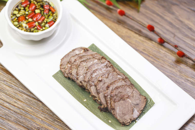 长方形白瓷盘装的蘸汁牛脊肉图片