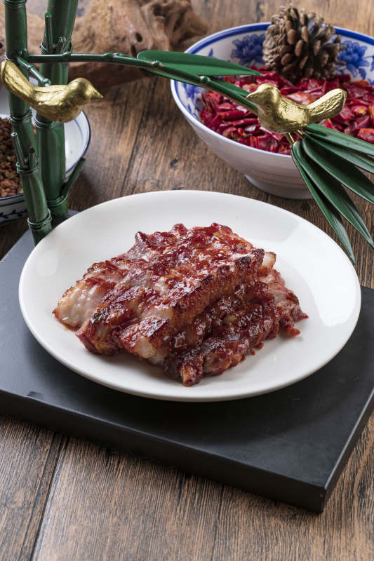 米花色瓷盘装的蜜汁叉烧肉摆放在樟木砧板上图片