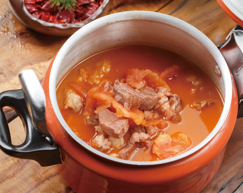 橙色不锈钢铁锅装的西红柿炖牛腩图片