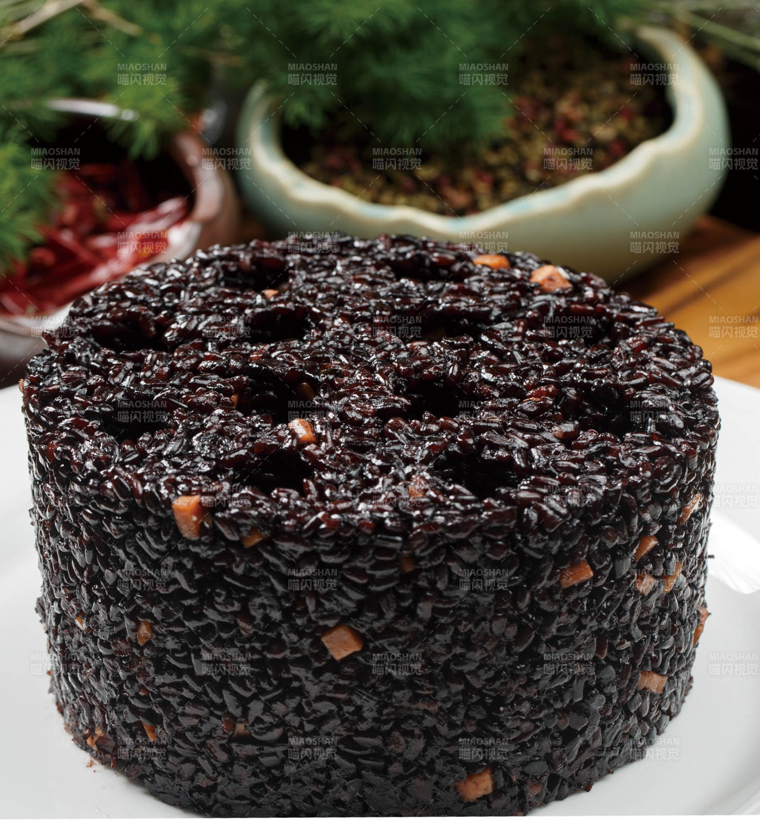 白色圆瓷盘装的蜂窝煤造型的黑米饭团图片