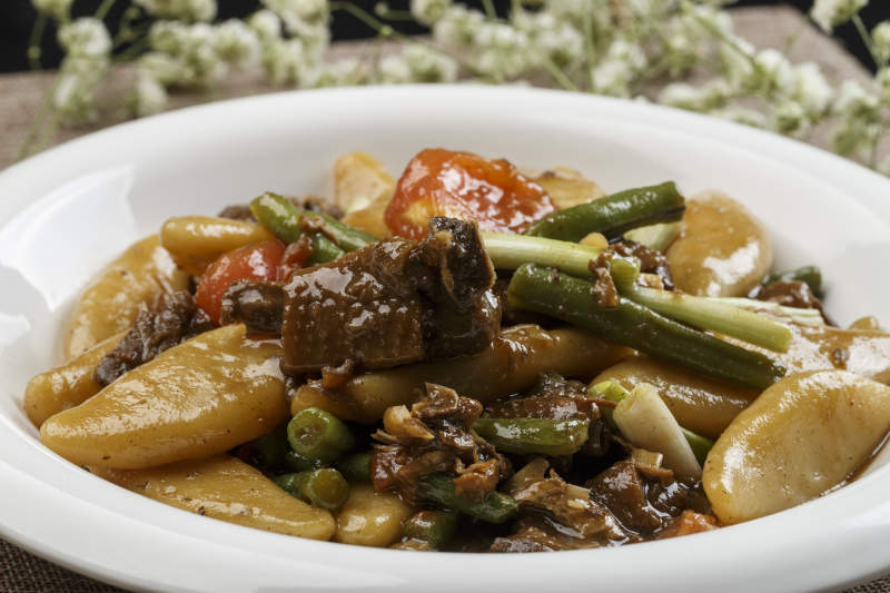 白色瓷盘装的豆角红烧肉炖山药鱼图片