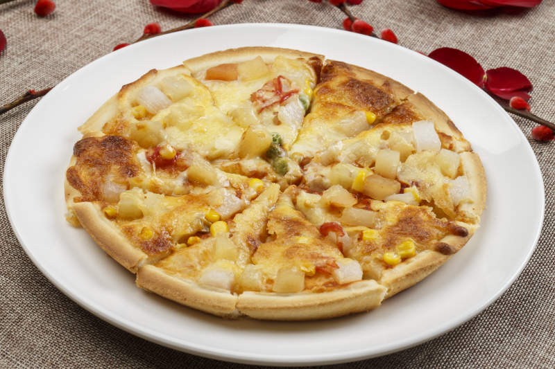白色瓷盘装的自制玉米火腿披萨图片