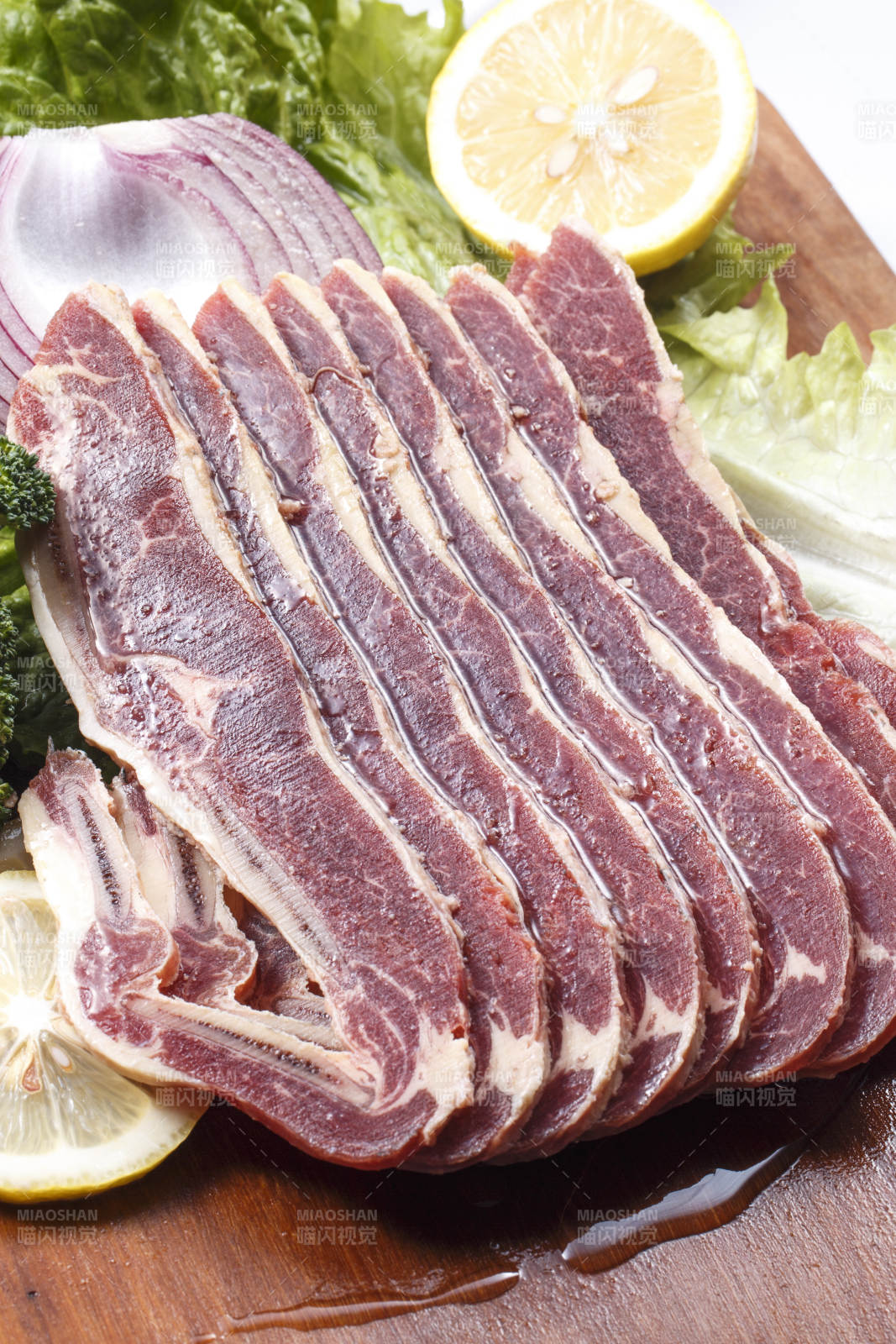 搭配柠檬洋葱生菜的牛肋排摆放在木质砧板上图片