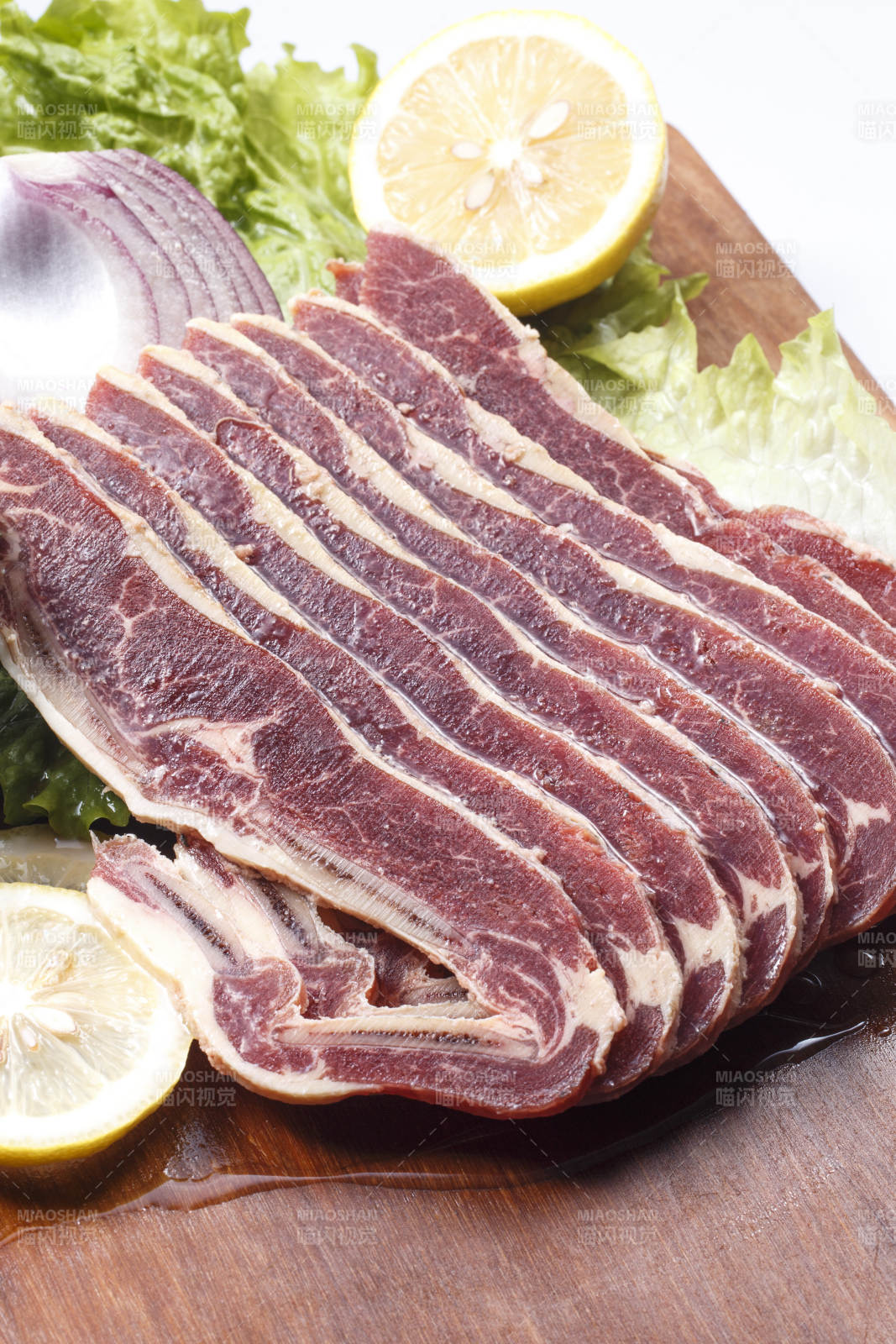 搭配柠檬洋葱生菜的牛肋排摆放在木质砧板上图片