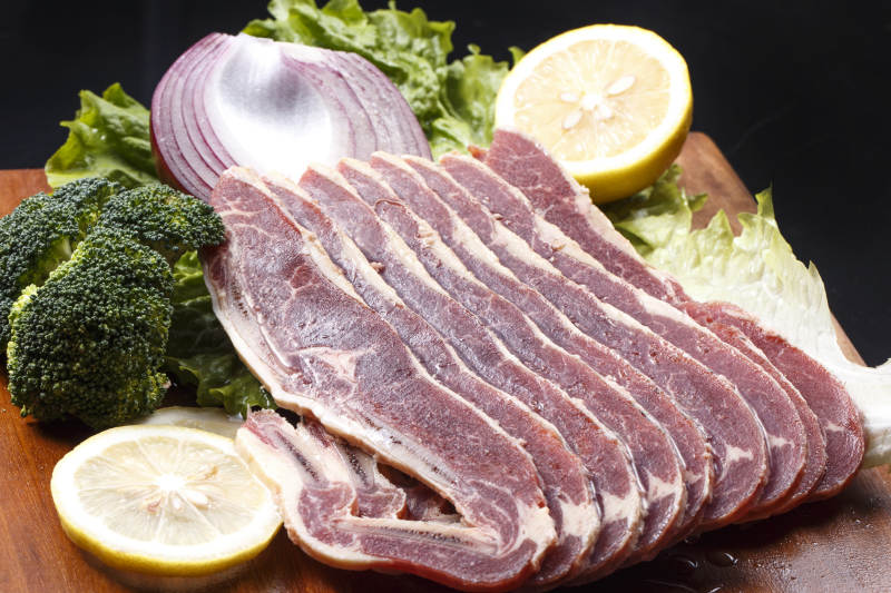 搭配柠檬洋葱生菜的牛肋排摆放在木质砧板上图片