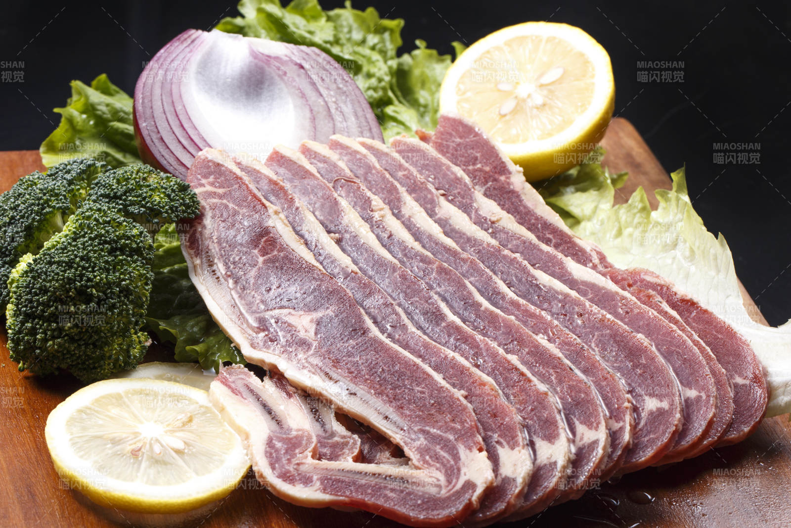 搭配柠檬洋葱生菜的牛肋排摆放在木质砧板上图片