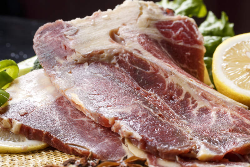 黑色背景草垫上的T骨牛排配柠檬图片