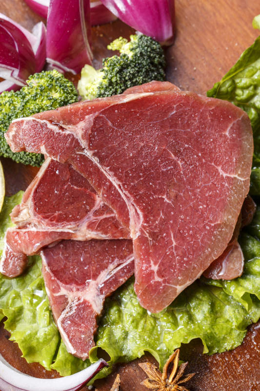 搭配洋葱生菜的牛米胧脍摆放在木质砧板上图片