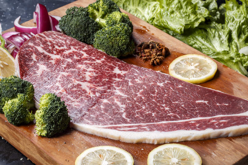 牛臀肉摆放在木质砧板上图片