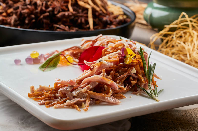 陈旧木板上的方瓷盘装的风味手撕兔图片