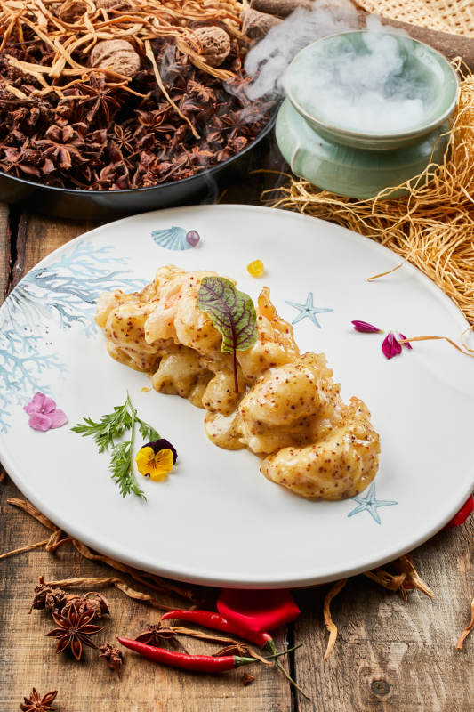 陈旧木板上的圆形瓷盘装的藜麦焗虾球图片