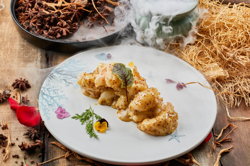 陈旧木板上的圆形瓷盘装的藜麦焗虾球图片