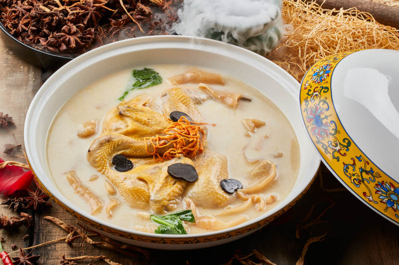 陈旧木板上的圆瓷汤盆装的花胶葛根炖柴鸡汤图片